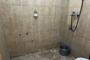 A small, tiled bathroom with a shower, a bucket, and a cup holder on the wall. - Hotel O Near Cilandak Town Square Formerly Sultan Residence Syariah (Jakarta)