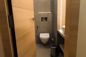 Une petite salle de bain comprenant des toilettes, une poubelle et un porte-serviettes.