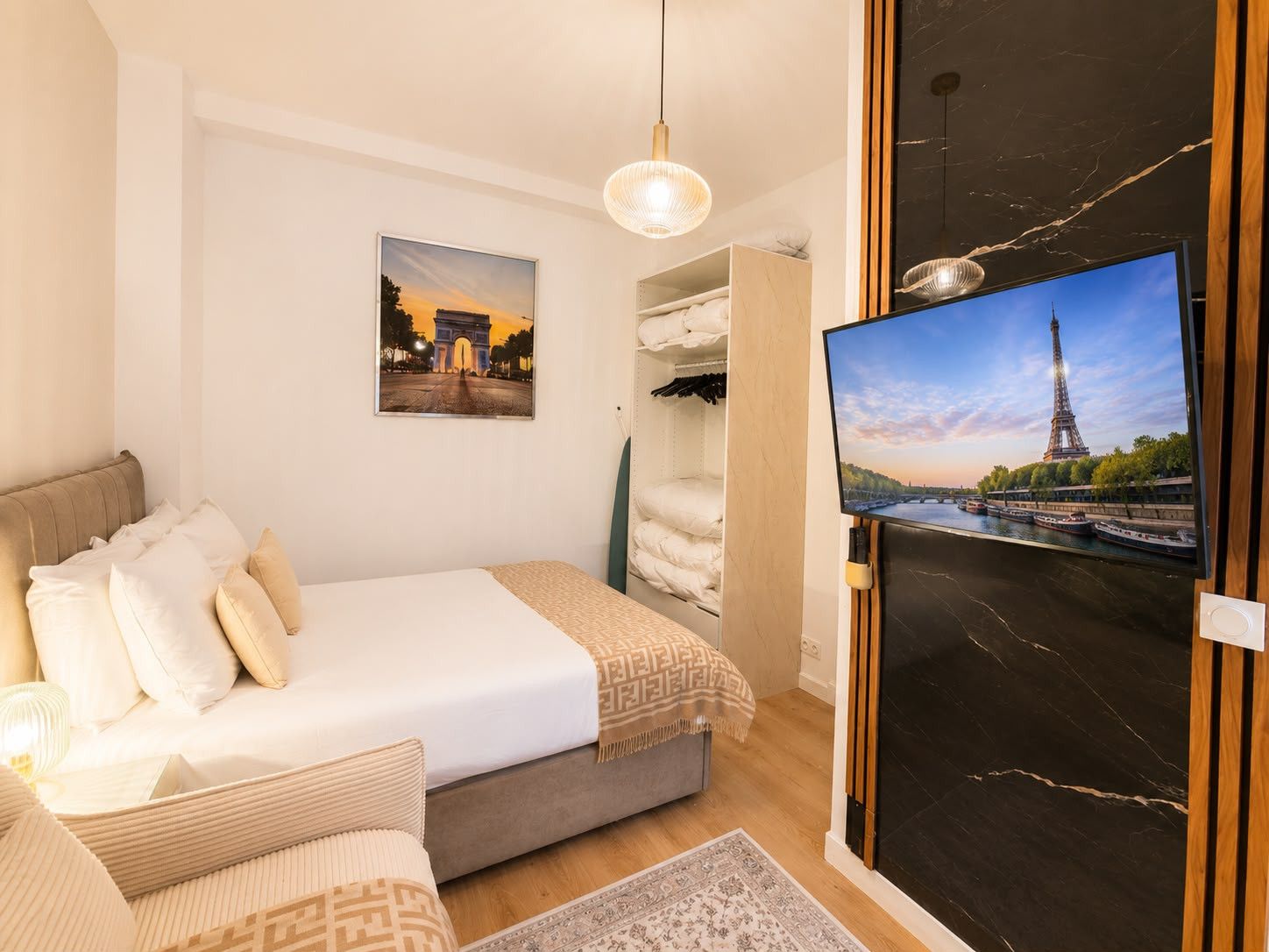 Une chambre avec un lit, une télévision, une armoire et une image de la Tour Eiffel.