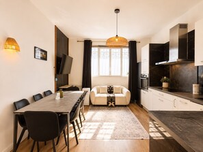 Une cuisine moderne avec un coin repas, un canapé et un téléviseur fixé au mur.
