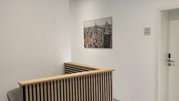 A reception area with a wooden slatted desk, a cityscape painting on the wall, and a door labeled '101'.