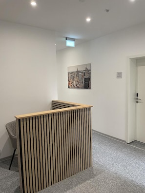 A reception area with a wooden slatted desk, a cityscape painting on the wall, and a door labeled '101'. - Hotel am Bahnhof Stuttgart-ditzingen (Ditzingen)