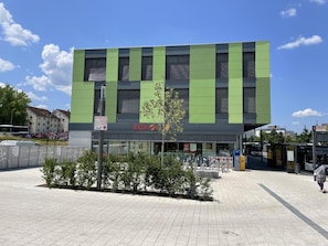A modern building with a green and black facade, a sign for 'ECKER', and a bicycle parking area. - Hotel am Bahnhof Stuttgart-ditzingen (Ditzingen)