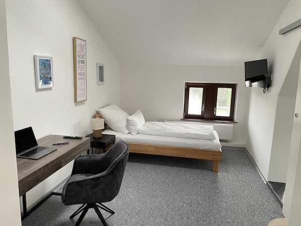 A small, modern room with a bed, a desk, and a chair. There are framed pictures on the wall and a TV mounted above the bed. - Hotel am Bahnhof Stuttgart-ditzingen (Ditzingen)