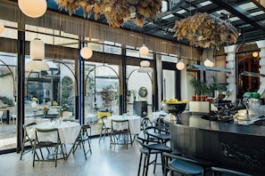 En modern restauranginteriör med runda bord, stolar och hängande blomsterdekorationer.