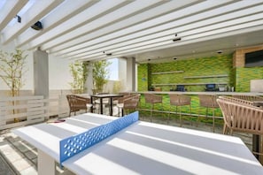 An outdoor patio area with a white table, chairs, and a blue bench. There is a kitchen area with a green backsplash and a bar. - The Adele Palazzo Suite at Palms Place (Las Vegas)