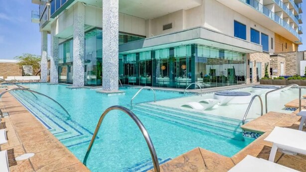 Um hotel moderno com piscina, área de estar externa e fachada de vidro.