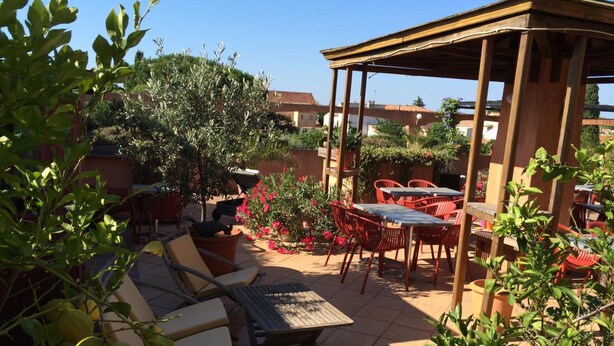 An outdoor patio area with seating arrangements, including a table and chairs, surrounded by greenery and potted plants. - Hotel and Spa Le Gambetta (Paris)