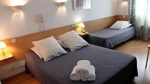 A hotel room with two beds, each with a pillow and a lamp on a bedside table.
