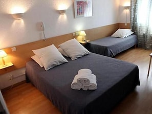 Une chambre d’hôtel avec deux lits, chacun étant équipé d’un oreiller et d’une lampe sur une table de chevet.