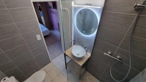 A compact bathroom with a toilet, a sink, and a shower area.