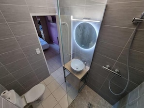 Une petite salle de bain comprenant des toilettes, un lavabo et un espace douche.