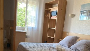A bedroom with two beds, a wooden wardrobe, and a window with curtains. - Hotel and Spa Le Gambetta (Paris)