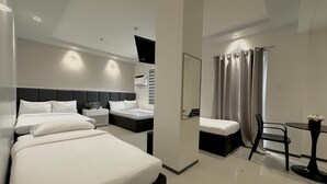 A modern hotel room with two beds, a small table, and a shower area. - Central Block Inn (Bacolod)