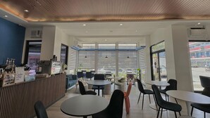A modern cafe interior with a wooden ceiling, large windows, and a variety of seating arrangements. - Central Block Inn (Bacolod)