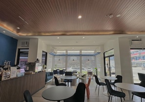 A modern cafe interior with a wooden ceiling, large windows, and a variety of seating arrangements. - Central Block Inn (Bacolod)
