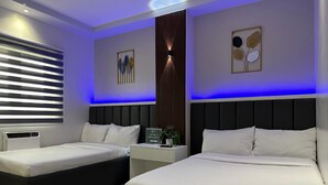 A modern bedroom with two beds, a nightstand, a wall-mounted lamp, and a window with blinds. - Central Block Inn (Bacolod)
