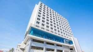 Een meerlaags hotel met een modern design, met een opvallende glazen gevel en verschillende balkons.