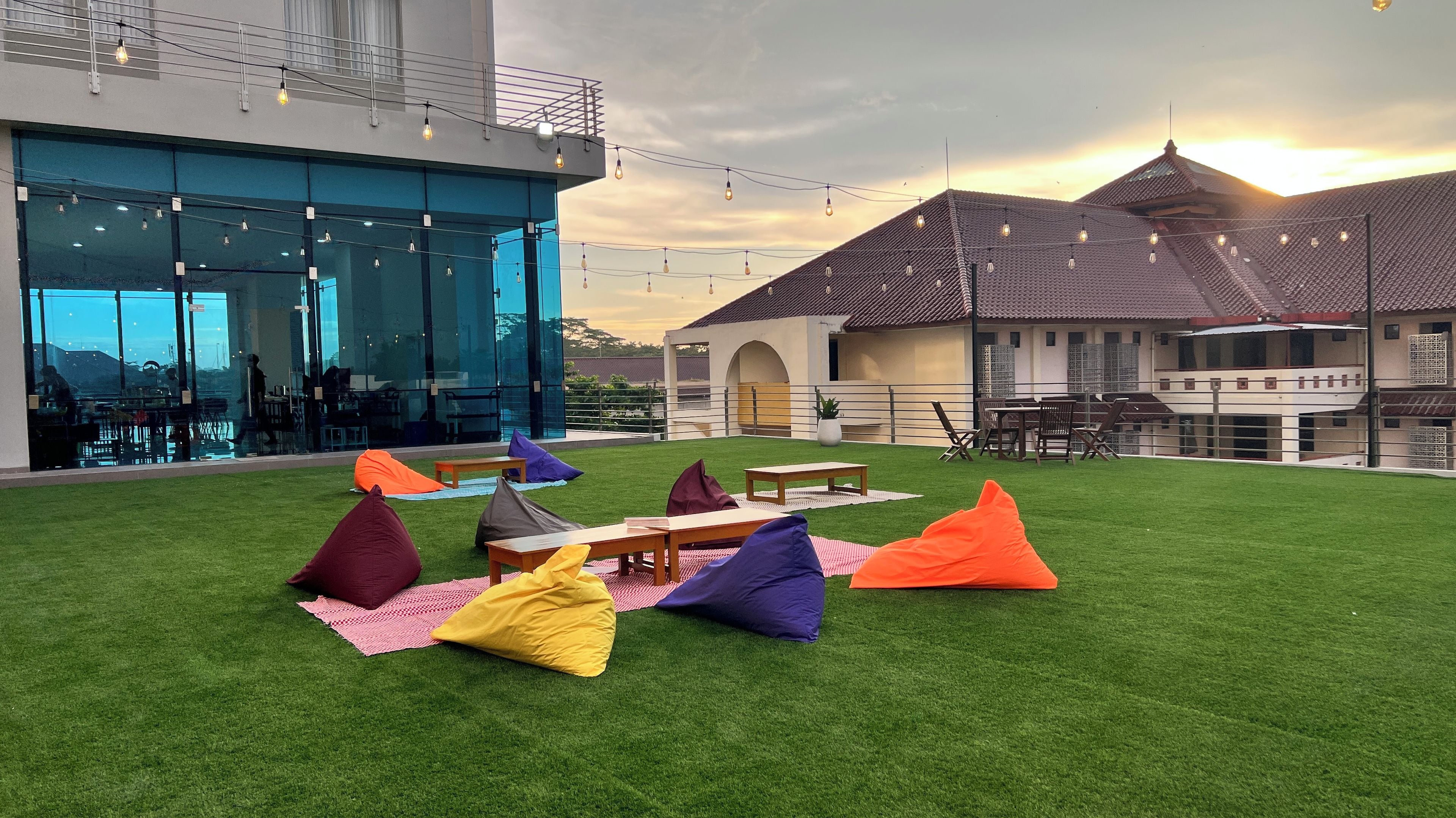 An outdoor seating area with green artificial grass, tables, and colorful bean bags.