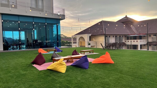 Een terras met kunstgras, tafels en kleurrijke loungestoelen.