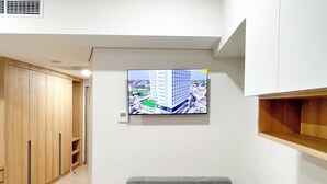 Una sala de estar moderna con un sofá gris, armarios de madera, un televisor montado en la pared y una pequeña mesa.
