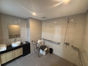 A modern bathroom with a sink, mirror, toilet, and shower. - University Hotel UMY (Depok)