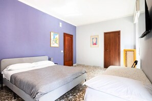 Quarto com duas camas, televisão e uma porta.
