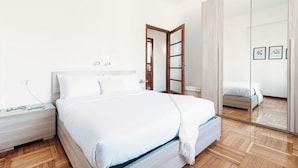 A modern bedroom with a bed, bedside table, and a large mirror. - Terrazza Rooftop (Como)