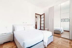 Une chambre à coucher moderne avec un lit, une table de chevet et un grand miroir.