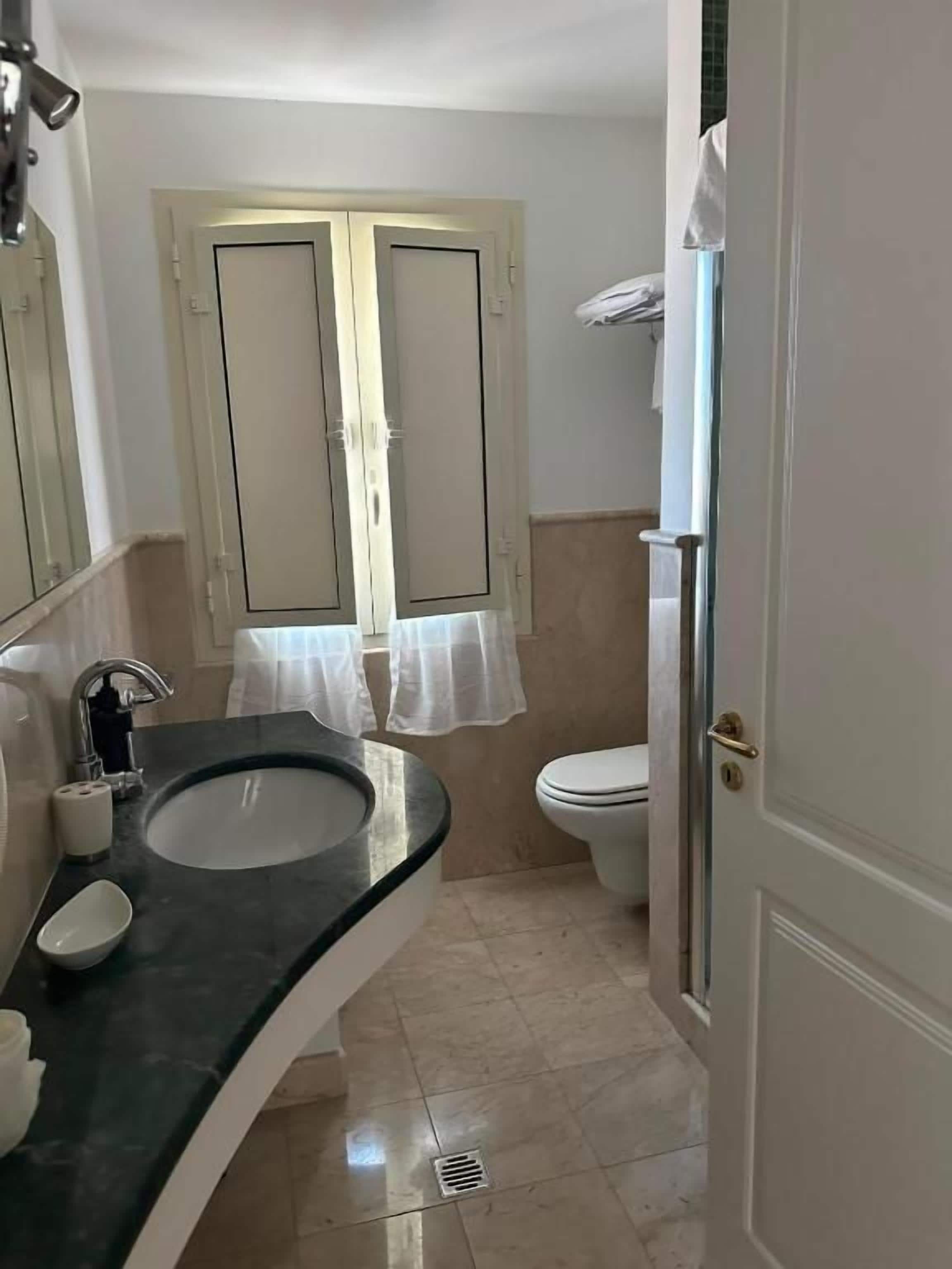 A bathroom with a sink, toilet, and a shower area.