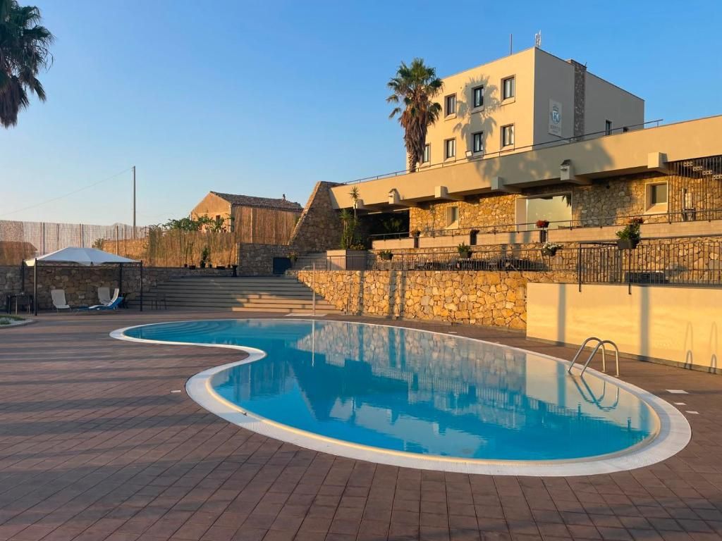 A swimming pool with a stone wall and a building with a balcony.