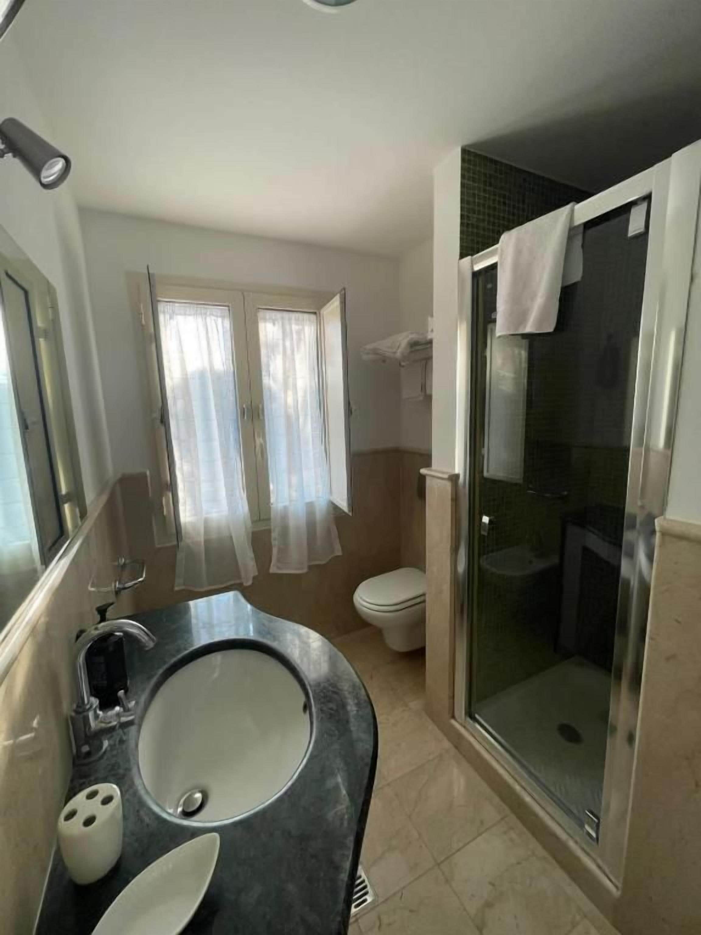Un baño con ducha envuelta en vidrio, un lavabo con espejo y un inodoro.