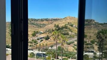 Blick aus einem Fenster auf einen Swimmingpool und eine hügelige Landschaft.