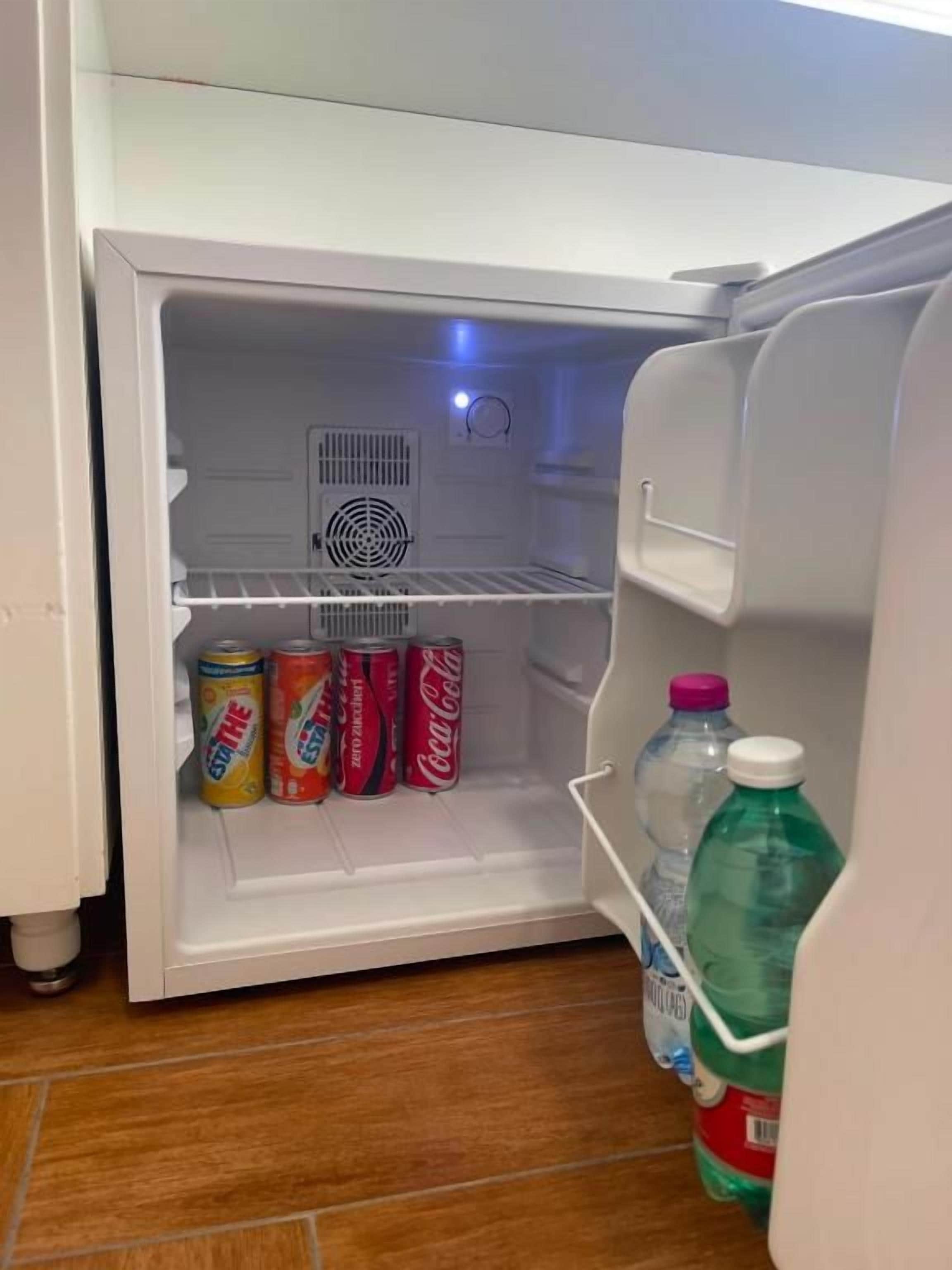 Ein offener Kühlschrank mit Getränken und einer Wasserflasche darin.