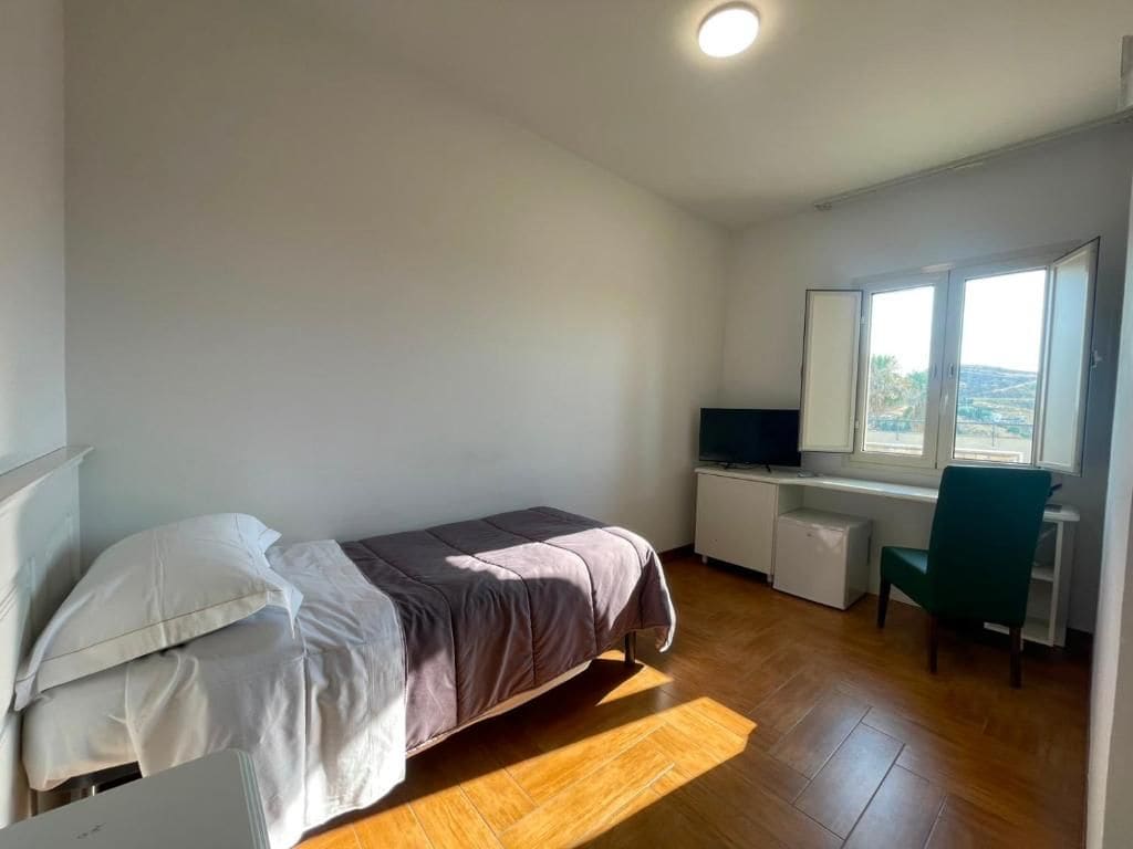 Ein Schlafzimmer mit Bett, Schreibtisch, Stuhl und Fernseher.