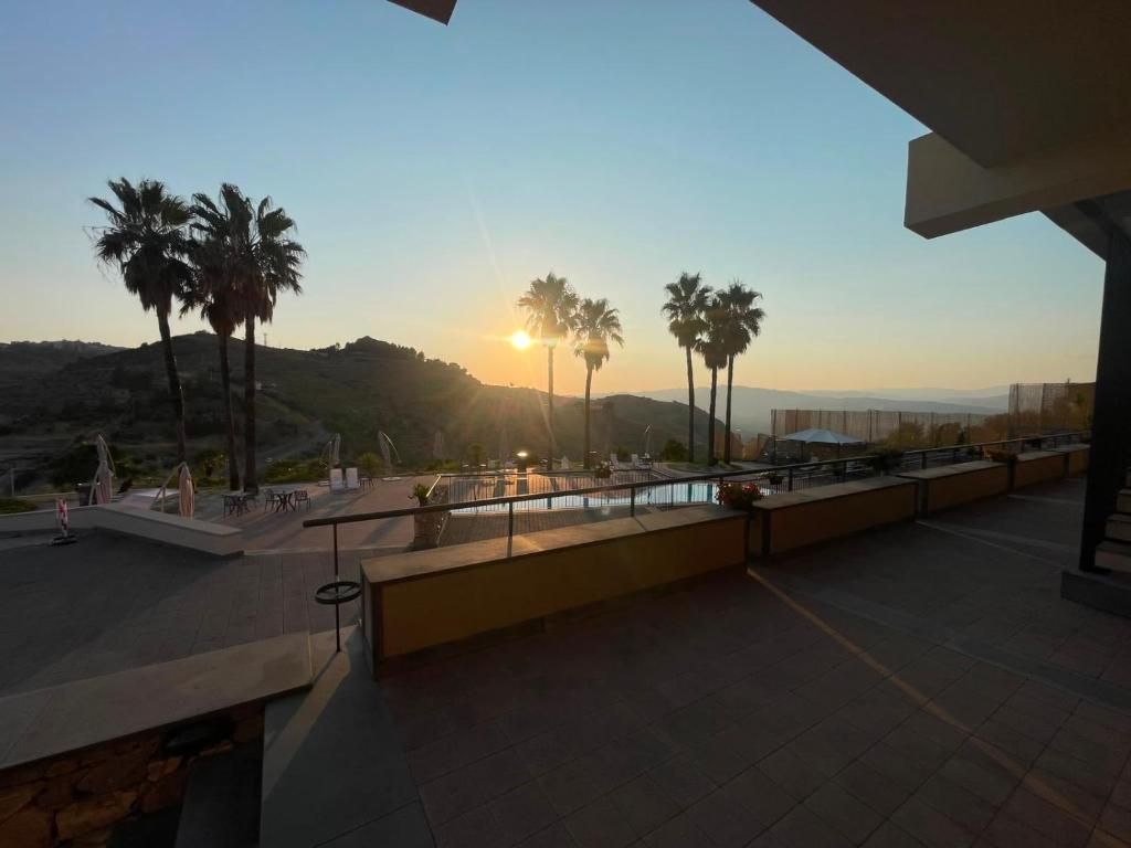 Una terraza con vistas a palmeras y al atardecer.