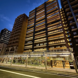 Un immeuble à plusieurs étages doté d’une architecture moderne, avec une série de balcons et une galerie couverte.