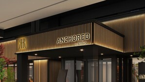 Fachada moderna de edifício com o nome 'ANCHORED by RIHGA' em destaque.