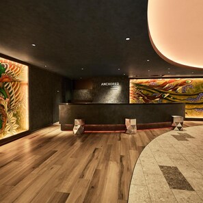Un espace d’accueil doté d’un comptoir sombre, d’un plancher en bois et d’une grande fresque murale.