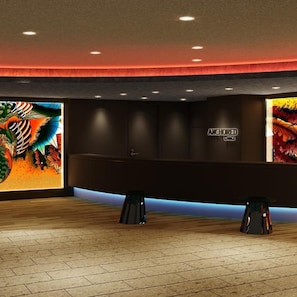 Un'area reception con un banco, due sgabelli e una parete decorata con un'opera d'arte colorata.