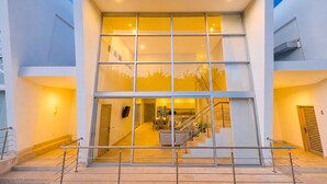 Un bâtiment moderne doté d’une façade en verre, d’un escalier menant à un niveau supérieur et d’un espace cuisine visible.