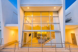 Un edificio moderno con fachada de vidrio, una escalera que lleva a un nivel superior y un área de cocina visible.