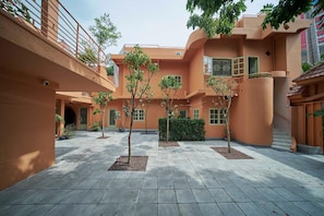 A courtyard with a tiled floor, trees, and a building with balconies. - M Village Living Dien Bien Phu (Ho Chi Minh Municipality)
