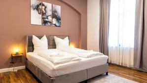Een slaapkamer met een bed, nachtlampen, een nachtkastje en een raam met gordijnen.