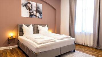 Ein modernes Schlafzimmer mit Bett, Nachttischlampen, einem Nachttisch und Kunstwerken an der Wand.