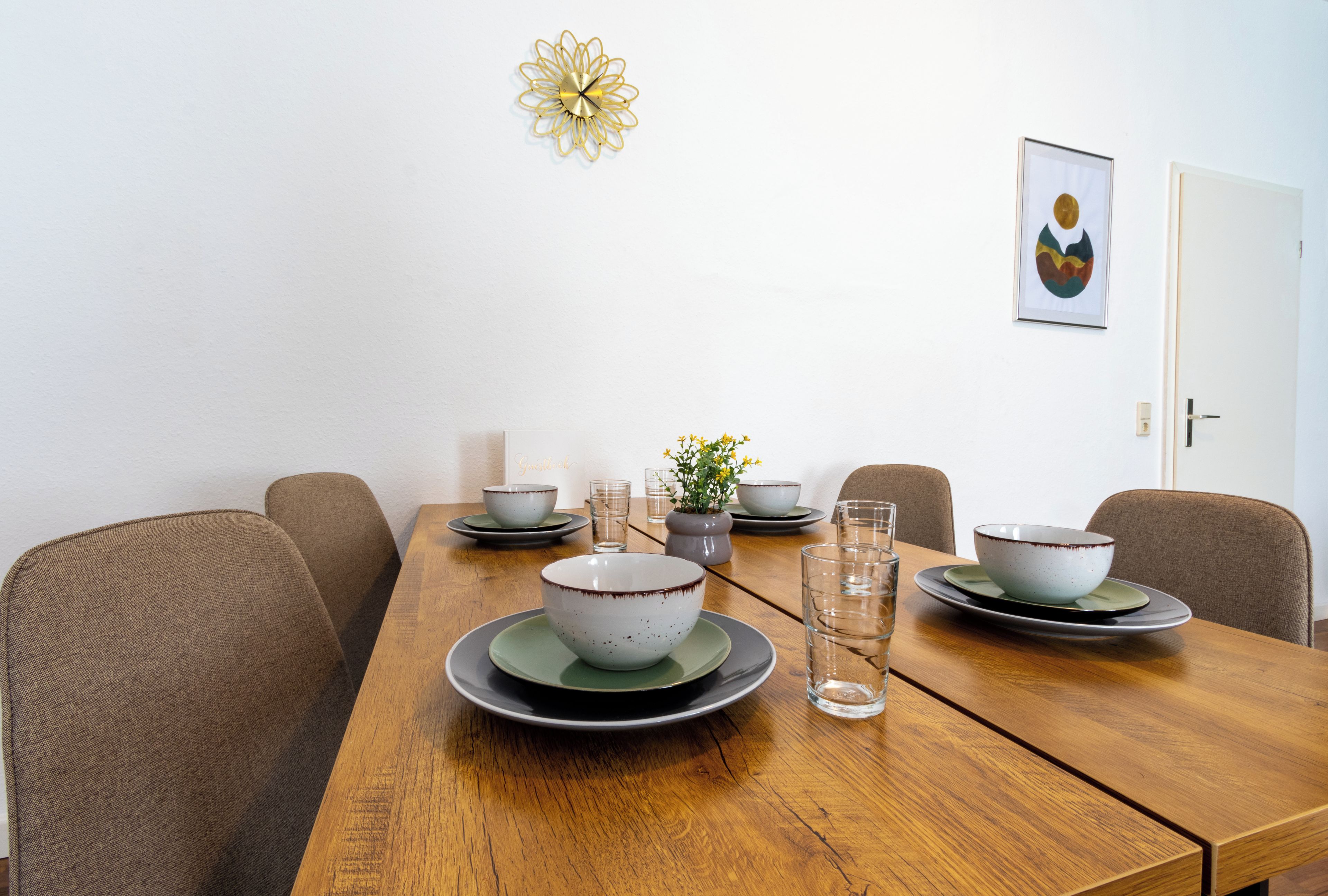 A dining table with bowls, glasses, and a potted plant.