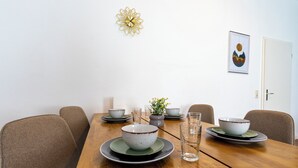 Een eettafel met kommen, glazen en een potplant.