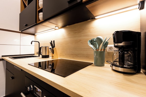 A modern kitchen with a black induction cooktop, a coffee maker, and a knife block.