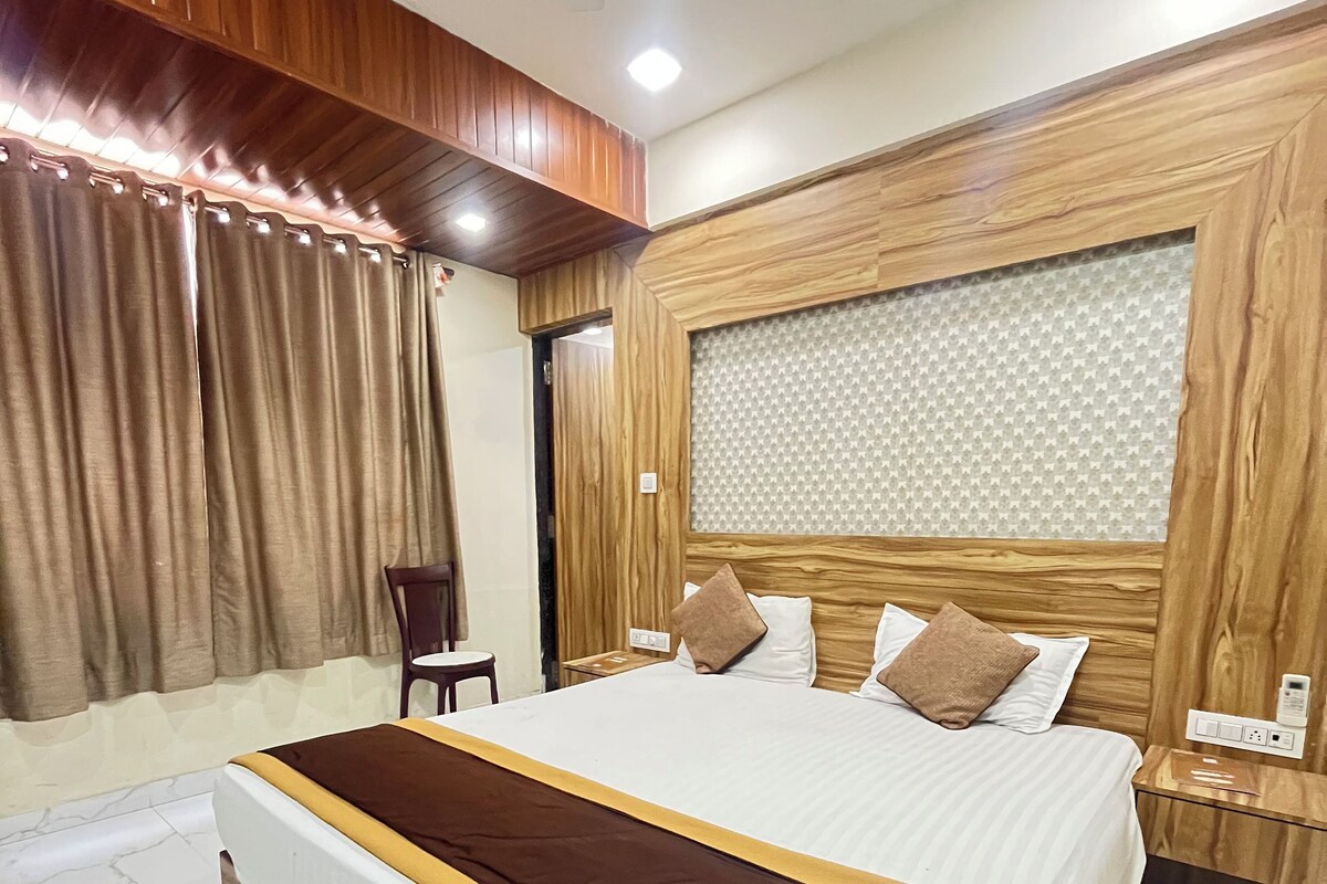 Habitación de hotel con una cama grande, cabecero de madera y piso de mármol.