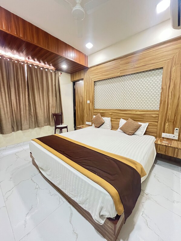 Habitación de hotel con una cama grande, cabecero de madera y piso de mármol.